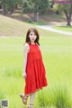 A woman in a red dress standing in a field.