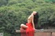 A woman in a red dress sitting on a ledge.