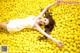 A woman laying in a pile of yellow lemons.