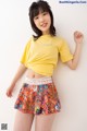 A woman wearing a yellow shirt and a colorful skirt.