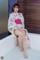 A woman in a kimono sitting in a bathtub.