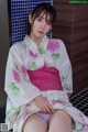 A woman in a white kimono sitting on a bench.