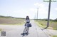 A woman riding a bike down a rural road.