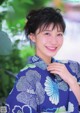 A woman in a blue kimono smiles at the camera.