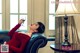 A woman in a red dress sitting on a couch holding a glass of wine.