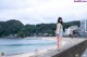 A woman standing on the edge of a concrete wall next to the ocean.