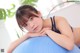 A young woman laying on top of an exercise ball.