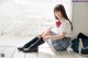 A woman in a school uniform sitting on the floor.