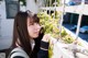 A young woman leaning against a fence with plants growing on it.