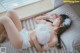 A woman laying on a bed in a white lingerie.